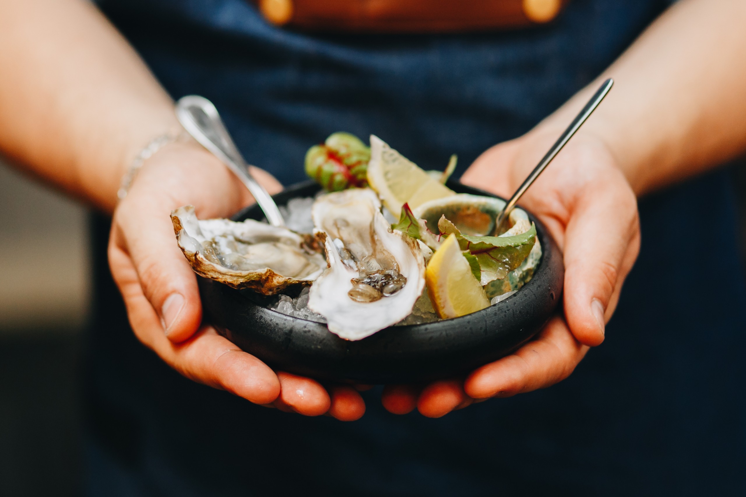 gorgeous oysters on a dark plate in men's hands